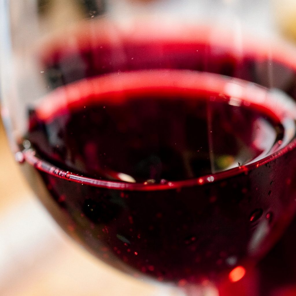 Wine glasses on a wooden bar top with soft candlelight and deep burgundy tones